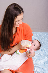 Image showing Young mother feeding bottle six-month baby girl