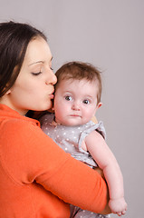 Image showing Happy mother kissing her daughter six-month