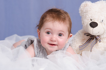 Image showing Six-month baby girl with teddy bear on sofa