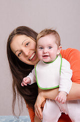 Image showing Young happy mother hugging baby girl in bib