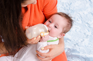 Image showing Mum feeds from a bottle six-month baby girl