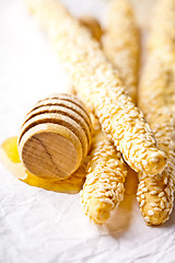 Image showing grissini with sesame seeds and honey dipper