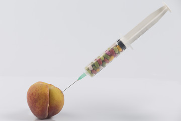 Image showing Peach and syringe with pills