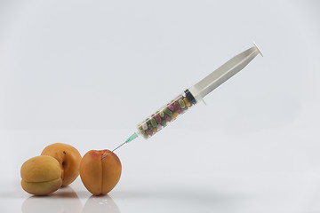 Image showing Apricots and syringe with pills