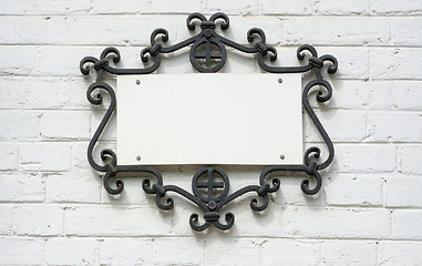 Image showing Information plate in forged frame on a brick wall.