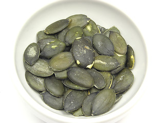 Image showing Pumpkin seeds in bowl of chinaware on white background