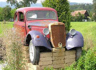 Image showing Rusted veteran car jacked up in the open countryside