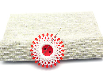 Image showing White thread with sewing needle on linon