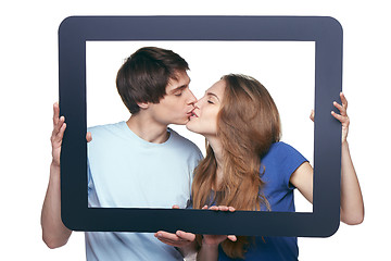 Image showing In love couple holding tablet frame kissing