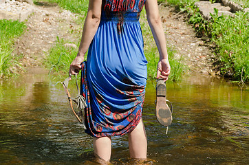 Image showing girl holds sandals wade barefoot flowing stream 