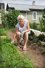 Image showing Mature woman sitting on a chair of his garden