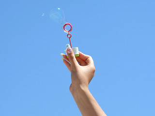 Image showing Female hand and soap bubbles on a background of the blue sky