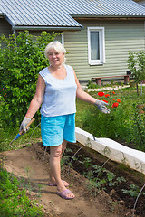 Image showing Elderly woman stands in the midst of the garden