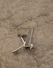 Image showing shopping cart dumped in mud at side of river