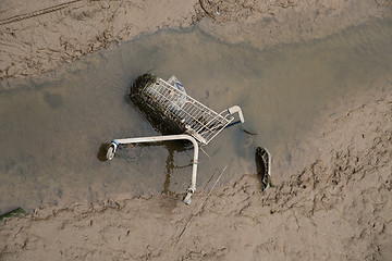 Image showing shopping cart dumped in mud at side of river