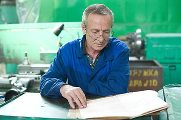 Image showing Elderly worker looks in drawing