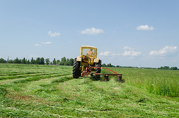 Image showing tractor make sharp turn and leaves cut grass tufts 