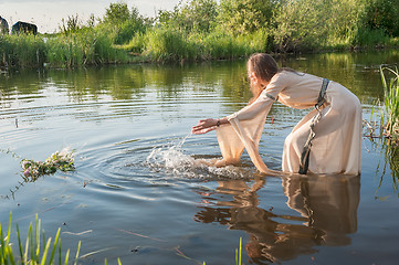 Image showing Attractive girl lowers wreath in water