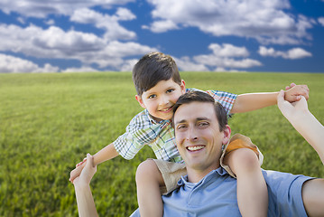 Image showing Mixed Race Father and Son Playing Piggyback on Grass Field