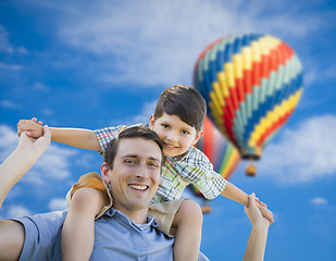 Image showing Father and Son Playing Piggyback with Hot Air Balloons Behind