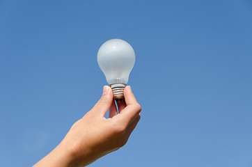 Image showing hand hold light bulb on blue sky background 