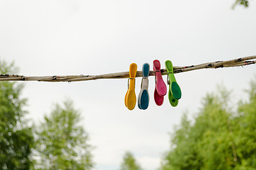 Image showing colorful clothes pins hanging on rope outdoor 