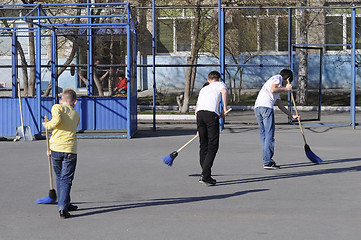 Image showing Teenagers sweep the yard with sweepers during a community work d