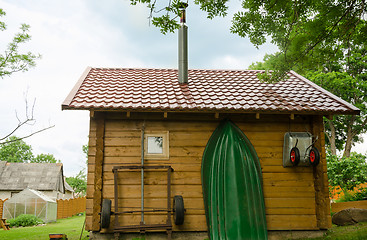 Image showing household utensil and boat hang on bathhouse wall  