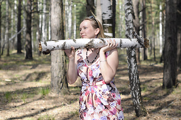 Image showing The young woman with a log in the wood.