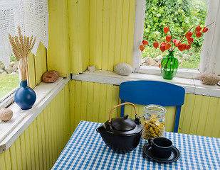 Image showing village kitchen and healing calendula tea on table 