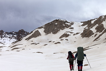 Image showing Two hikers on snowy plateau before storm