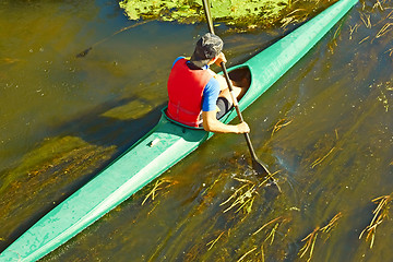 Image showing Canoeist floating on the overgrown river 