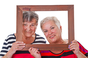 Image showing Two senior women looking through a picture frame