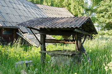 Image showing old derelict rural manhole covered with tall grass 