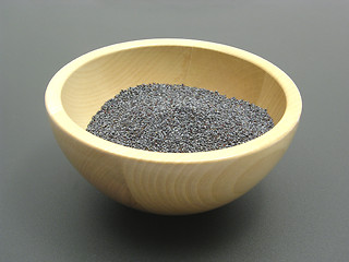 Image showing Wooden bowl with poppy seeds on a dull matting