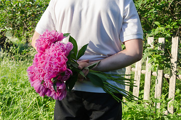 Image showing close up of man back with peony in hand 