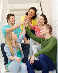 Image showing smiling students making high five gesture sitting