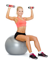 Image showing woman with dumbbells sitting on fitness ball