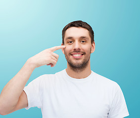 Image showing smiling young handsome man pointing to eyes