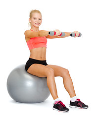 Image showing woman with dumbbells sitting on fitness ball