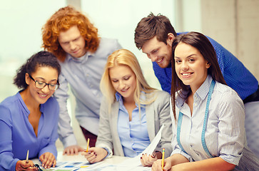 Image showing smiling creative team looking over clothes designs