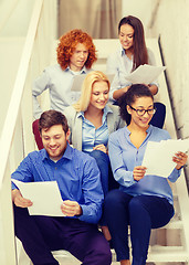 Image showing team with papers and take away coffee on staircase