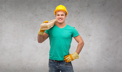 Image showing smiling manual worker in helmet with wooden boards