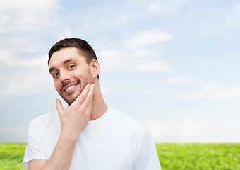 Image showing beautiful smiling man touching his face