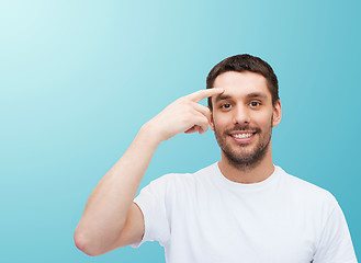 Image showing smiling young handsome man pointing to forehead