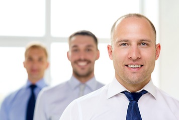 Image showing smiling businessman in office with team on back