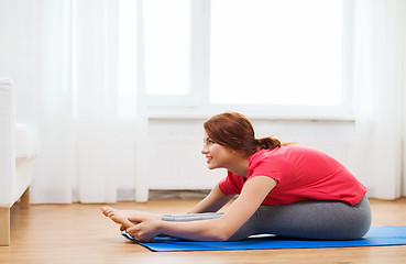 Image showing smiling teenage girl streching on floor at home