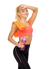 Image showing smiling sporty woman with towel and water bottle