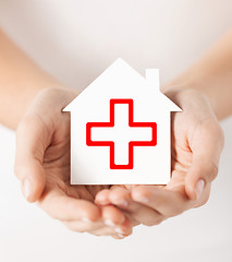 Image showing hands holding paper house with red cross