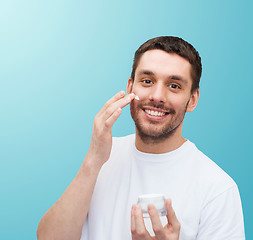 Image showing beautiful smiling man applyin cream